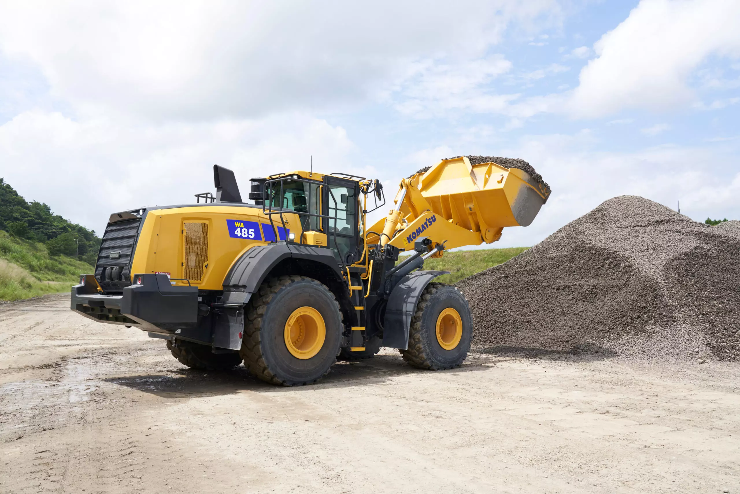 En komatsu-grävmaskin dumpar grus bredvid vägen